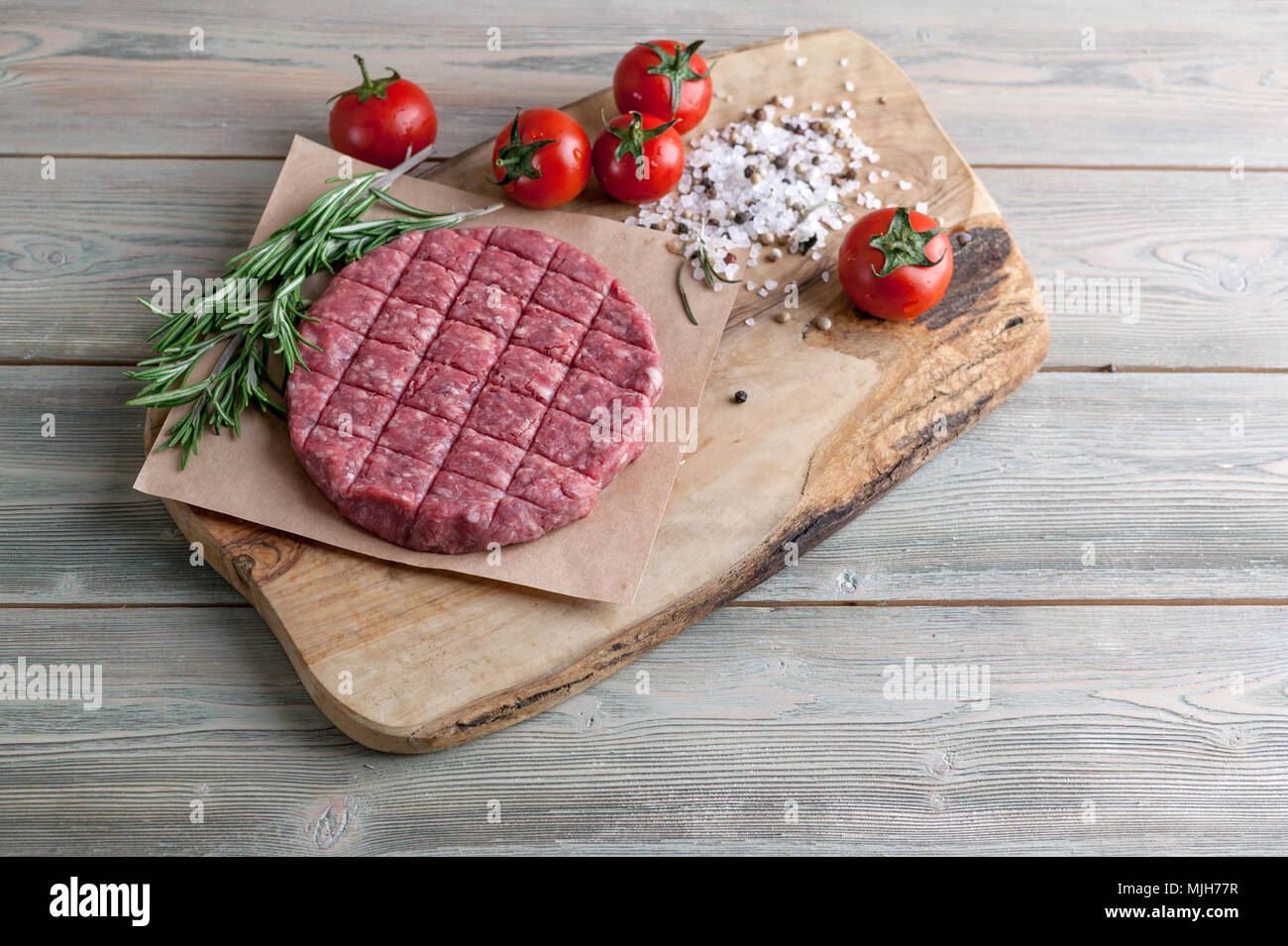 Die koteletts für Burger aus frischem Hackfleisch mit Gewürzen ende Kräutern auf einem Holztisch Stockfoto
