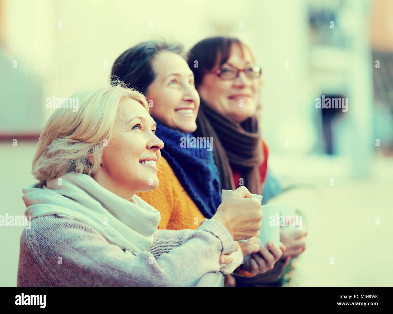 Gruppe von senior Freundinnen Teetrinken am Balkon und lächelnd. Blondine im Fokus Stockfoto