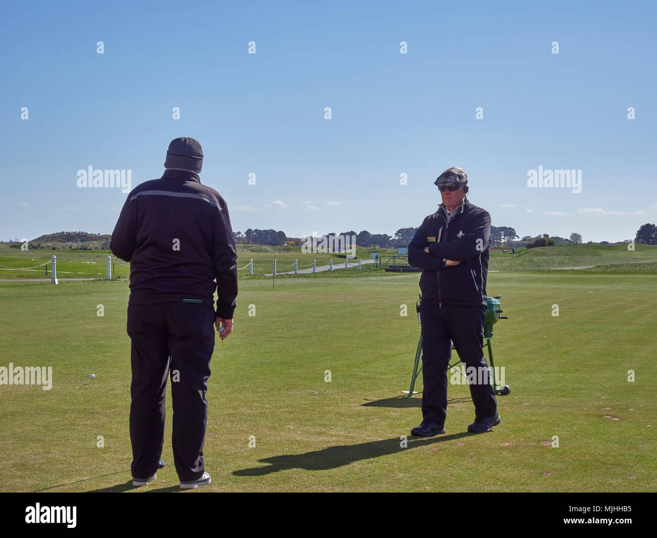 Ein Golfspieler und der offiziellen Carnoustie warten auf die 1.-T-Stück der Kurs Meisterschaft gestartet wird, während ein anderer Golfspieler zu Fahren vorbereitet wird. Schottland. Stockfoto