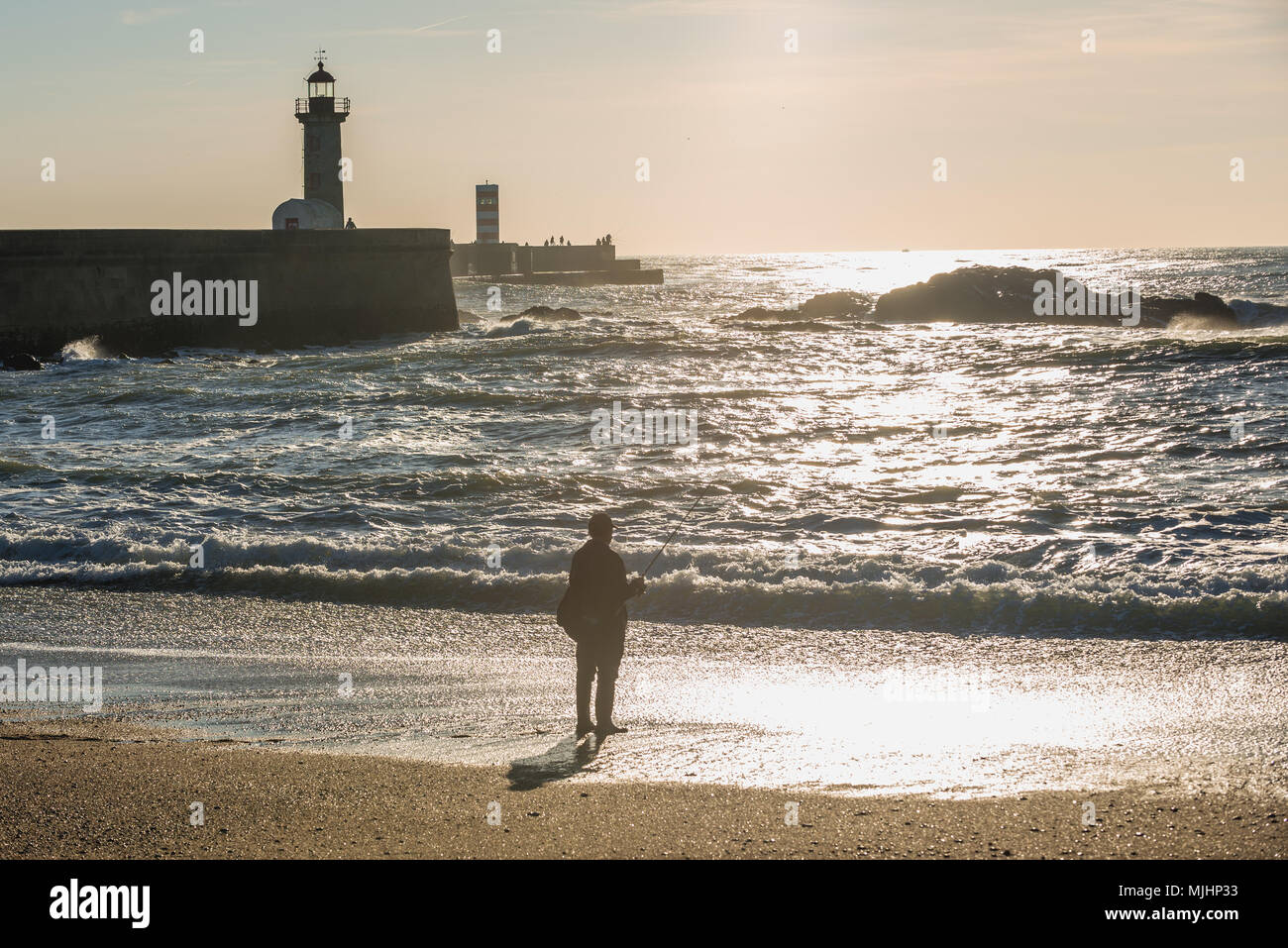 Mann Angeln vom Strand in Foz Douro Bezirk von Porto Stadt, zweitgrößte Stadt in Portugal. Ansicht mit Felgueiras Leuchtturm Stockfoto