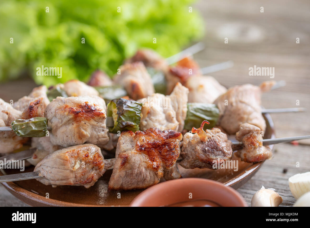 Zarte Shish Kebab aus Schweinefleisch auf dem offenen Feuer und frische Salatblätter gekocht. Noch immer leben auf einer hölzernen Hintergrund. Rustikal. Close-up. Stockfoto