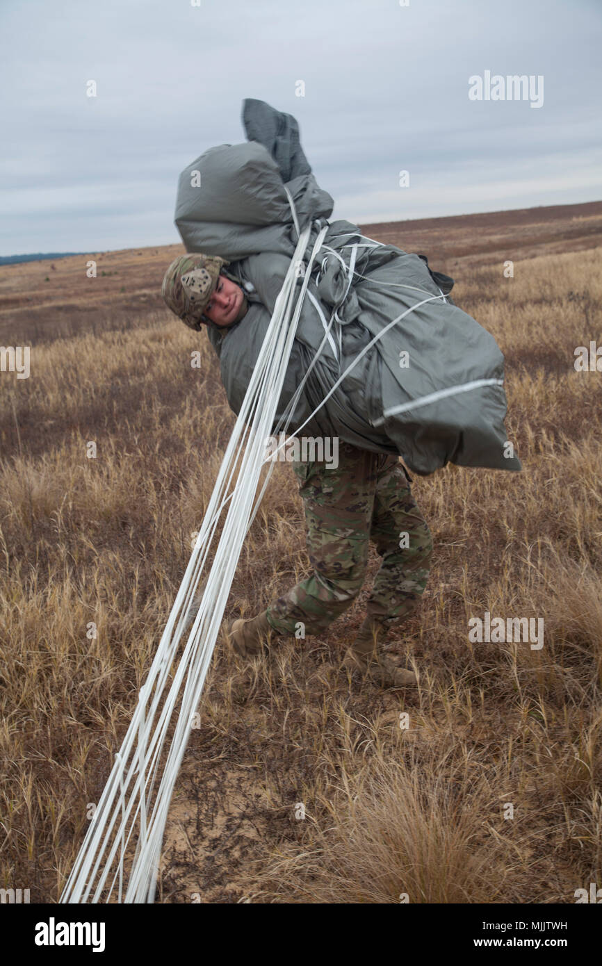 Us-Armee Fallschirmjäger Pfc. Cooper Käfig des Alpha Company, 1 Battalion, 505Th Parachute Infantry Regiment erholt sich sein Fallschirm nach einem erfolgreichen Sprung auf Sizilien Drop Zone für die 20. jährlichen Randy Oler Memorial Betrieb Spielzeug fallen, durch die US-Armee die zivilen Angelegenheiten & psychologische Operations Command (Airborne) gehostet, Dez. 2, 2017 in Fort Bragg, North Carolina. Betrieb Spielzeug Drop ist der weltweit größte kombinierten Betrieb und Soldaten erlaubt, die Möglichkeit, auf ihren militärischen beruflichen Spezialgebiet zu trainieren, pflegen ihre Bereitschaft, in die Luft und wieder zurück in die lokale Gemeinschaft zu geben. (U.S. Ein Stockfoto