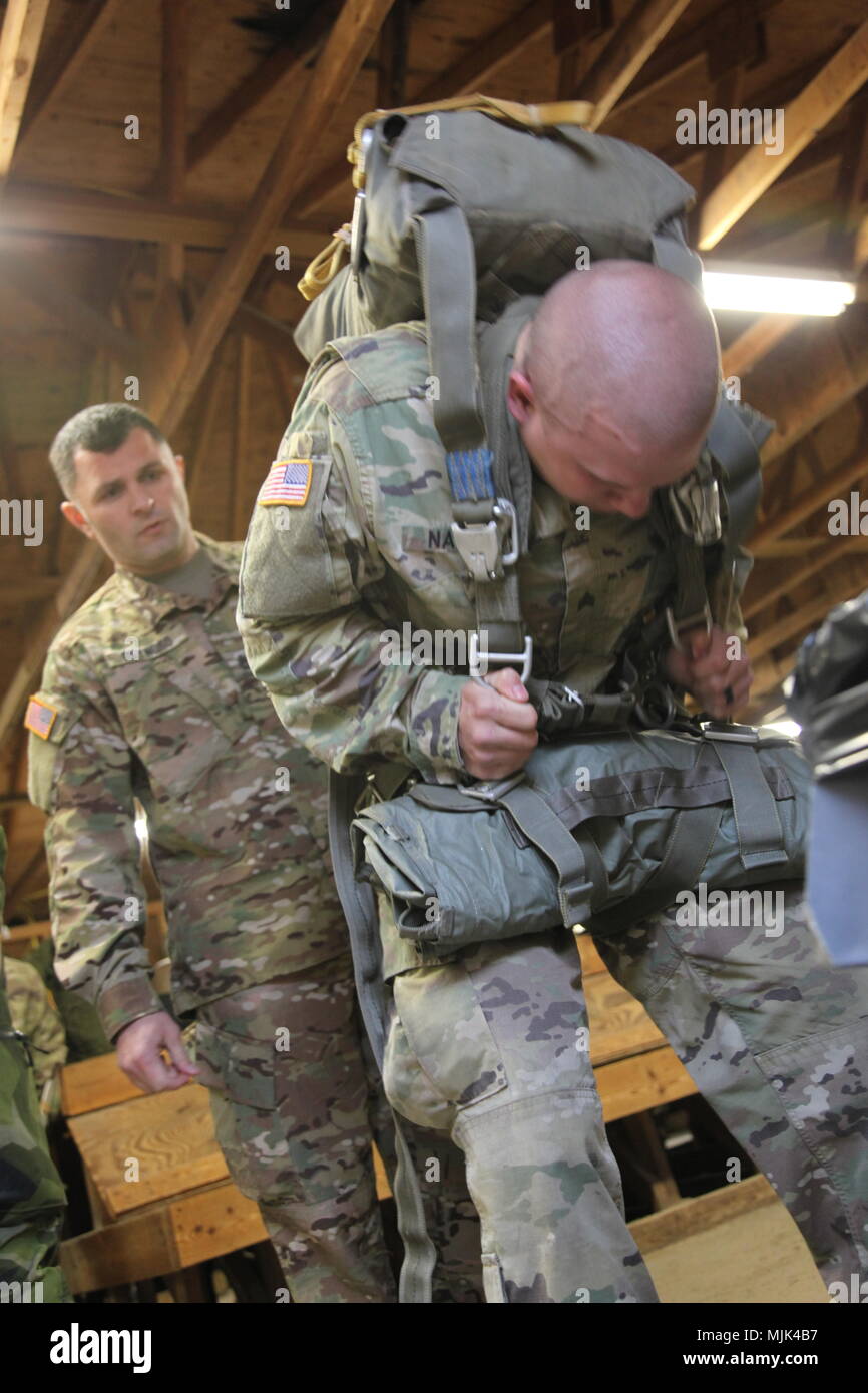 Us-Armee Fallschirmjäger don ihre fallschirme vor dem Jumpmaster persönliche Inspektion (JMPI) während der 20. jährlichen Randy Oler Memorial Betrieb Spielzeug Fallen, bewirtet durch die US-Armee die zivilen Angelegenheiten & psychologische Operations Command (Airborne), Dez. 6, 2017 MacKall Army Airfield, North Carolina. Betrieb Spielzeug Drop ist der weltweit größte kombinierten Betrieb mit neun Partner nation Fallschirmjäger teilnehmenden und Soldaten erlaubt, die Möglichkeit, auf ihren militärischen beruflichen Spezialgebiet zu trainieren, pflegen ihre Bereitschaft, in die Luft und wieder zurück in die lokale Gemeinschaft zu geben. (U.S. Armee Foto von Sgt John Jo Stockfoto