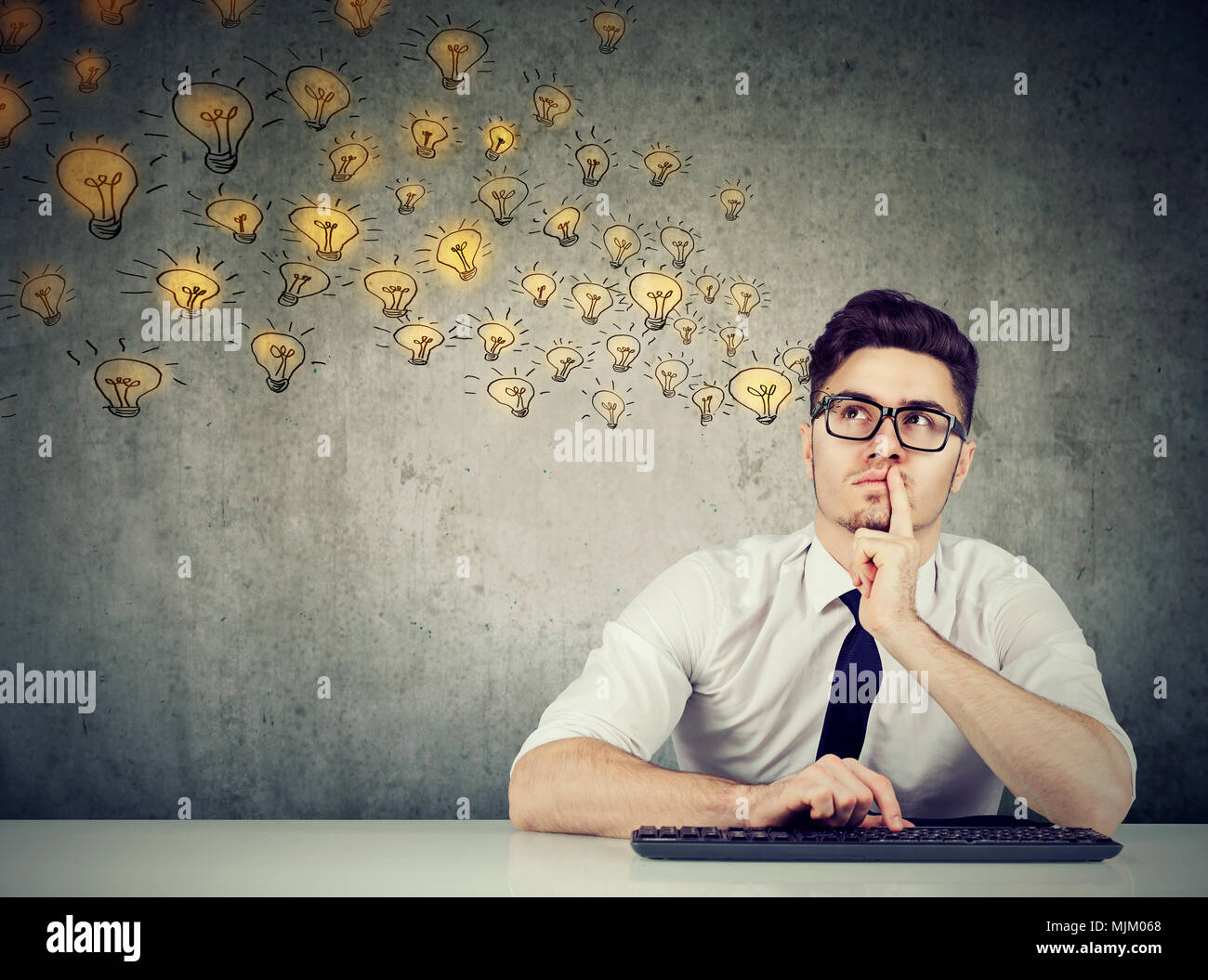 Junge nachdenklicher Mann in Gläsern am Tisch sitzen und denken über neue Ideen. Stockfoto