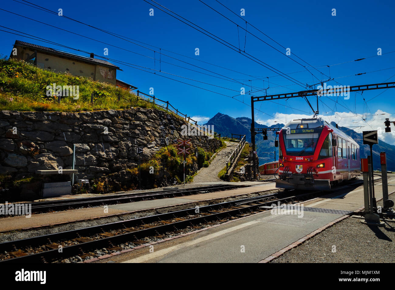 Poschiavo, Graubünden, Schweiz - 10 AUGUST 2016: Rote Zug der Rhätischen Bahn Einfahrt in die Station Alp Grum an einem sonnigen Tag im Sommer Stockfoto