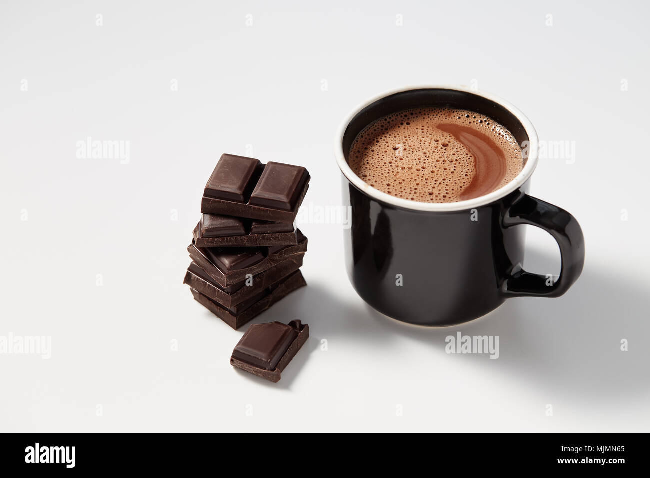 Schwarzer Kaffeebecher mit heißer Schokolade serviert mit Chunks von dunkler Schokolade Stockfoto