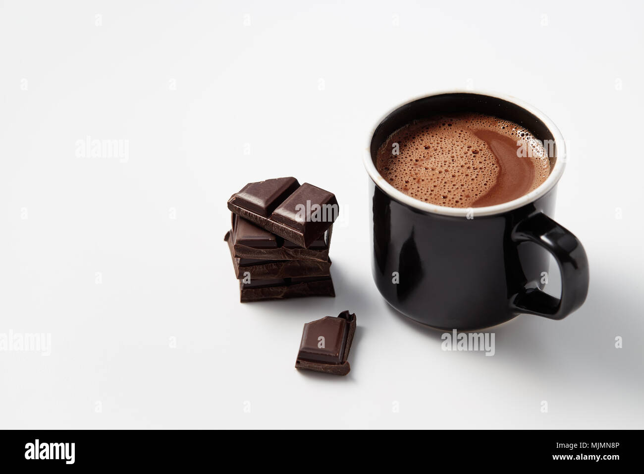 Schwarzer Kaffeebecher mit heißer Schokolade serviert mit Chunks von dunkler Schokolade Stockfoto