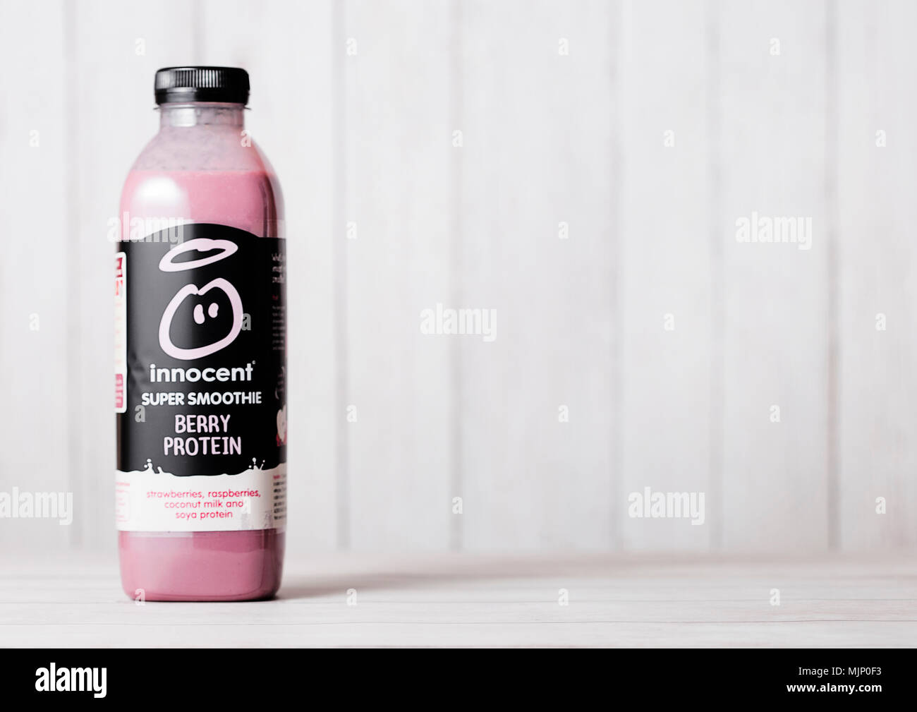 LONDON, Großbritannien - 03.Mai 2018: die Flasche von Unschuldigen Beeren smoothie Fruchtdrink mit Vitaminen auf Holzuntergrund mit frischen Beeren. Stockfoto