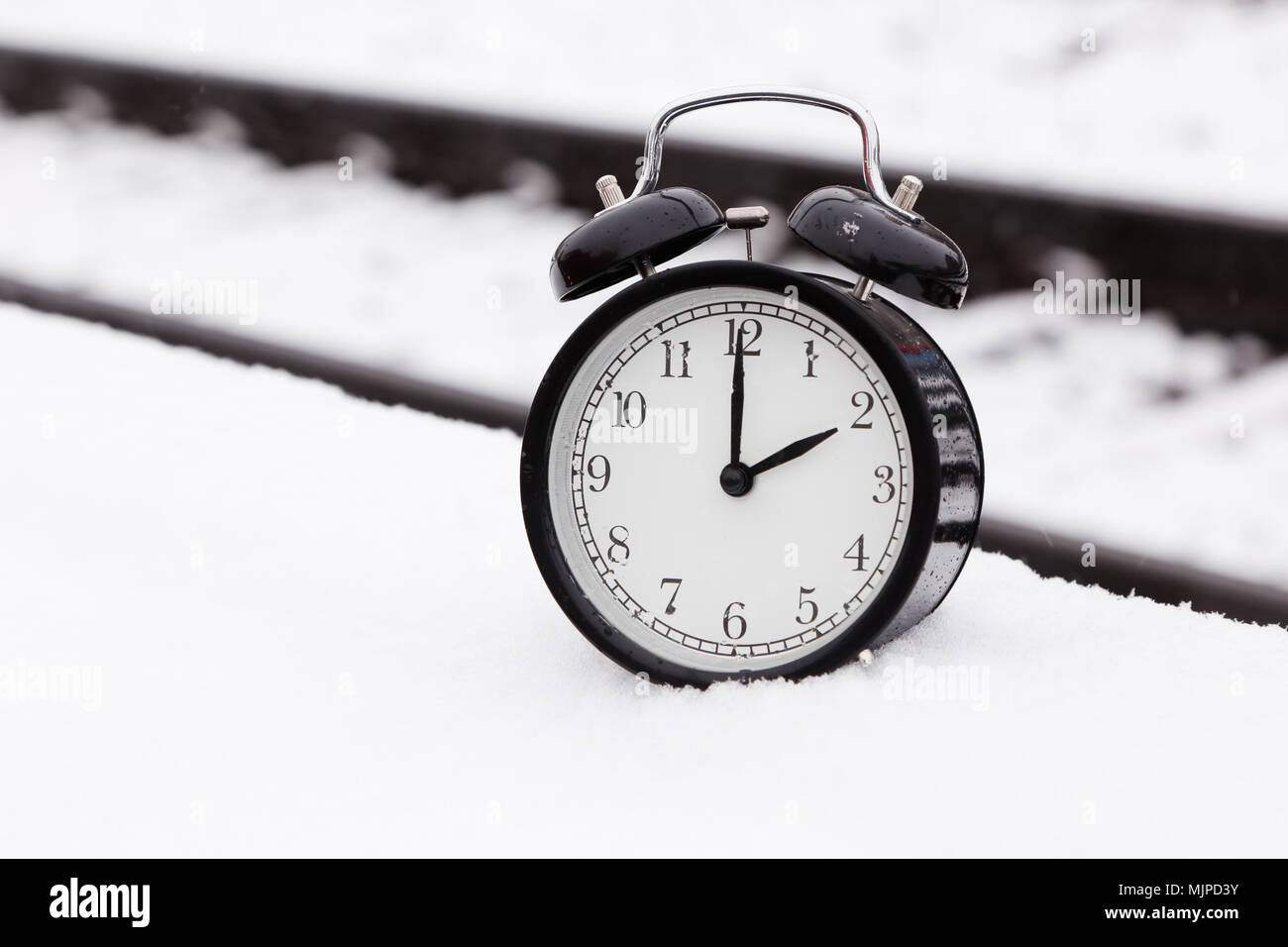 Eine schwarze Wecker auf Eisenbahnschienen draußen im Schnee. Stockfoto