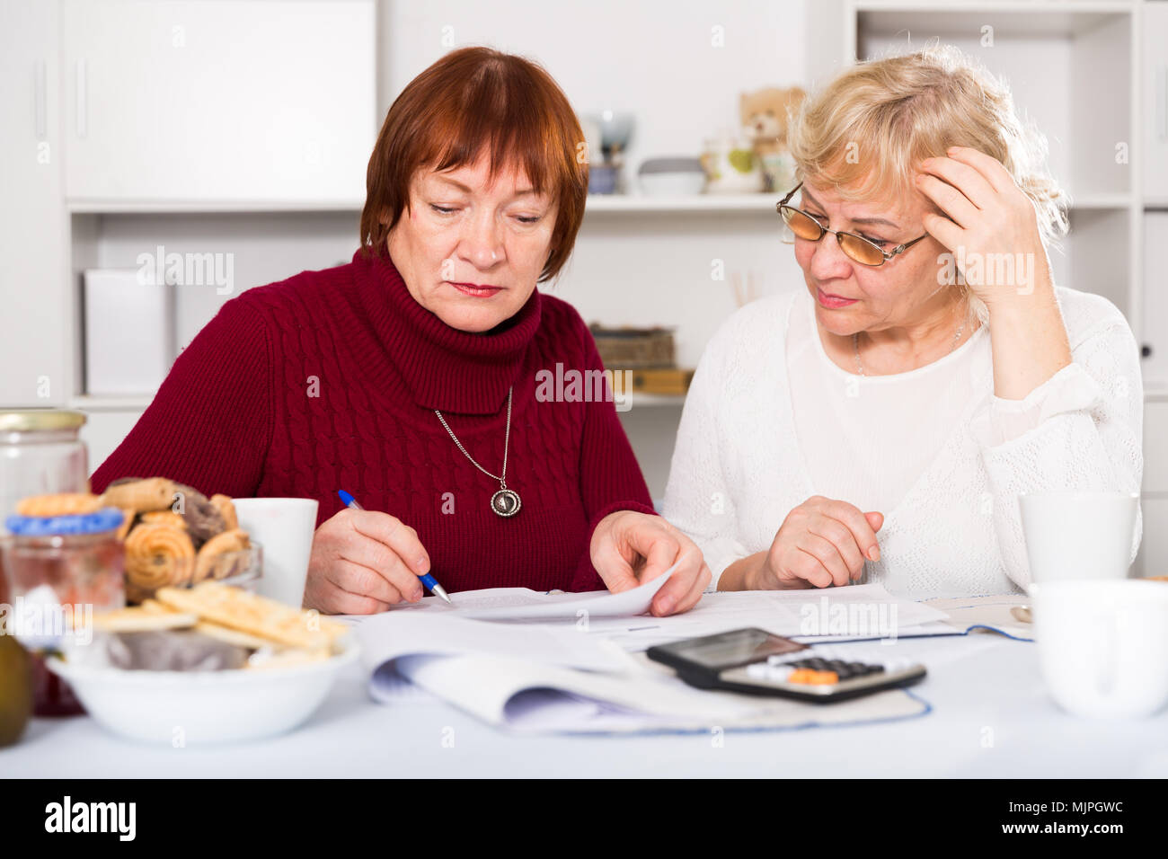 Verärgert älteren Damen aufmerksam lesen von Dokumenten, während zu Hause sitzen Stockfoto