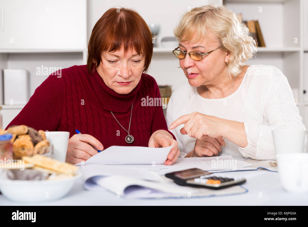 Zwei reife weibliche Freunde suchen besorgt an Papiere zu Hause Stockfoto