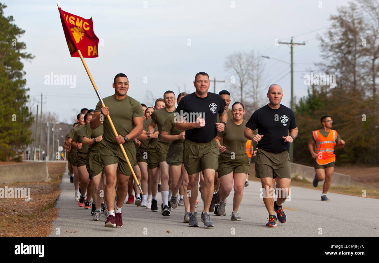 Mitarbeiter des United States Marine Corps, die der Personal Administration School zugewiesen wurden, führten am 15. Dezember 2017 einen Kommandolauf in Camp Johnson, North Carolina, durch, als Teil einer koordinierten Bemühung, die Teamarbeit innerhalb des Trainingskommandos zu stärken. Der archivierte Fotodruck zeichnet die Einheit auf, die sich während des geplanten physikalischen Konditionierungsereignisses in Formation bewegt. Stockfoto