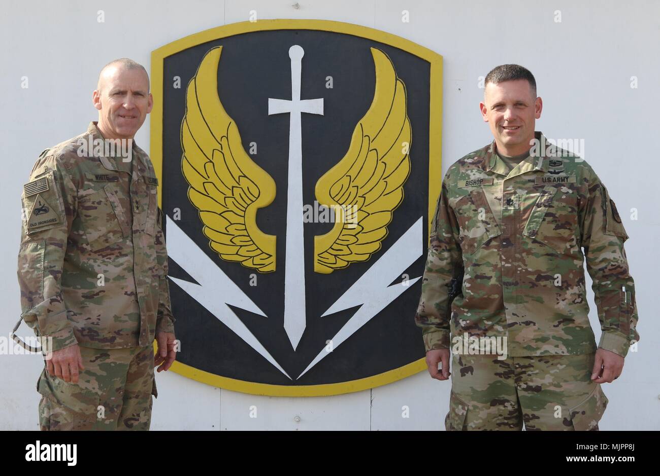 Die 449Th Combat Aviation Brigade Kommandeur Oberstleutnant Josef Bischof und die Combined Joint Forces Land Component Commander Generalmajor Robert Weiß für ein Bild vor der Einheit Insignien des 449Th CAB die Übertragung der Autorität des inhärenten lösen, um die Einheit zu bedeuten darstellen, um für die vielfältigen Betrieb vorzubereiten, den TOA-Signale die Übertragung von Verantwortung für Theater Luftverkehr auf den eingehenden 449Th CAB. CJTF-OIR ist die globale Koalition zu besiegen ISIS im Irak und in Syrien. (U.S. Armee Foto vom Kapitän Briana McFarland) Stockfoto