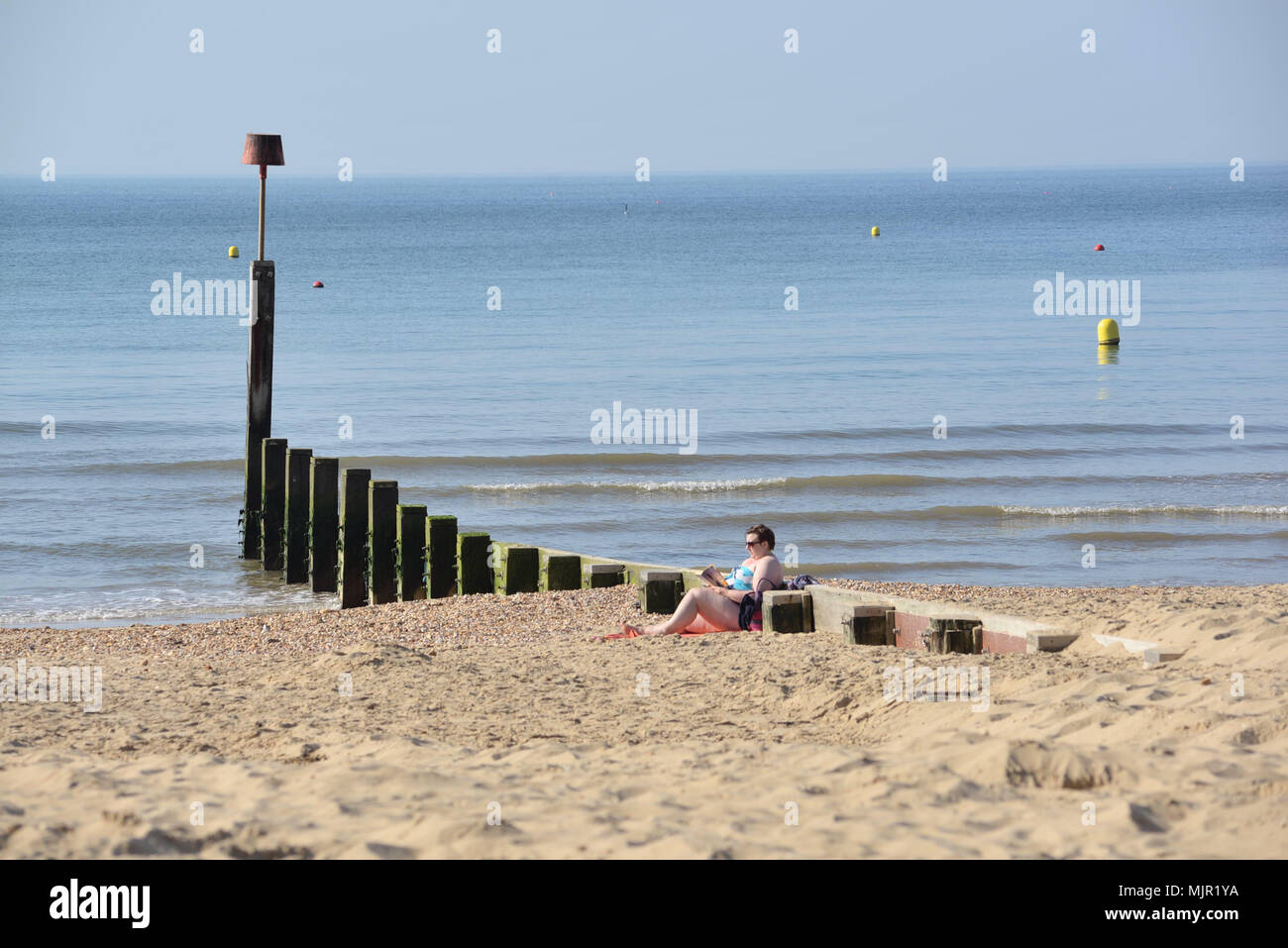 Boscombe, Bournemouth, Dorset, UK, 6. Mai 2018, Wetter: Morgen Sonnenschein an der Südküste auf, was die heißesten Mayday Bank Holiday Wochenende festgehalten werden könnte. Eine Frau entspannen am Strand neben einem ruhigen Meer. Stockfoto