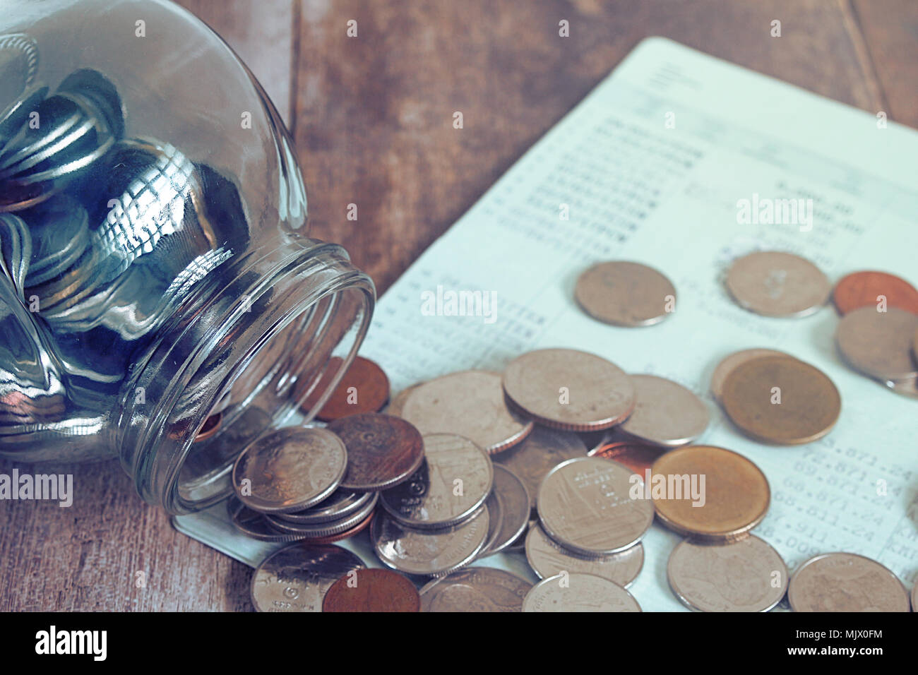 Geld Herausspritzen von Tasse Glas auf Buch Bank. Stockfoto