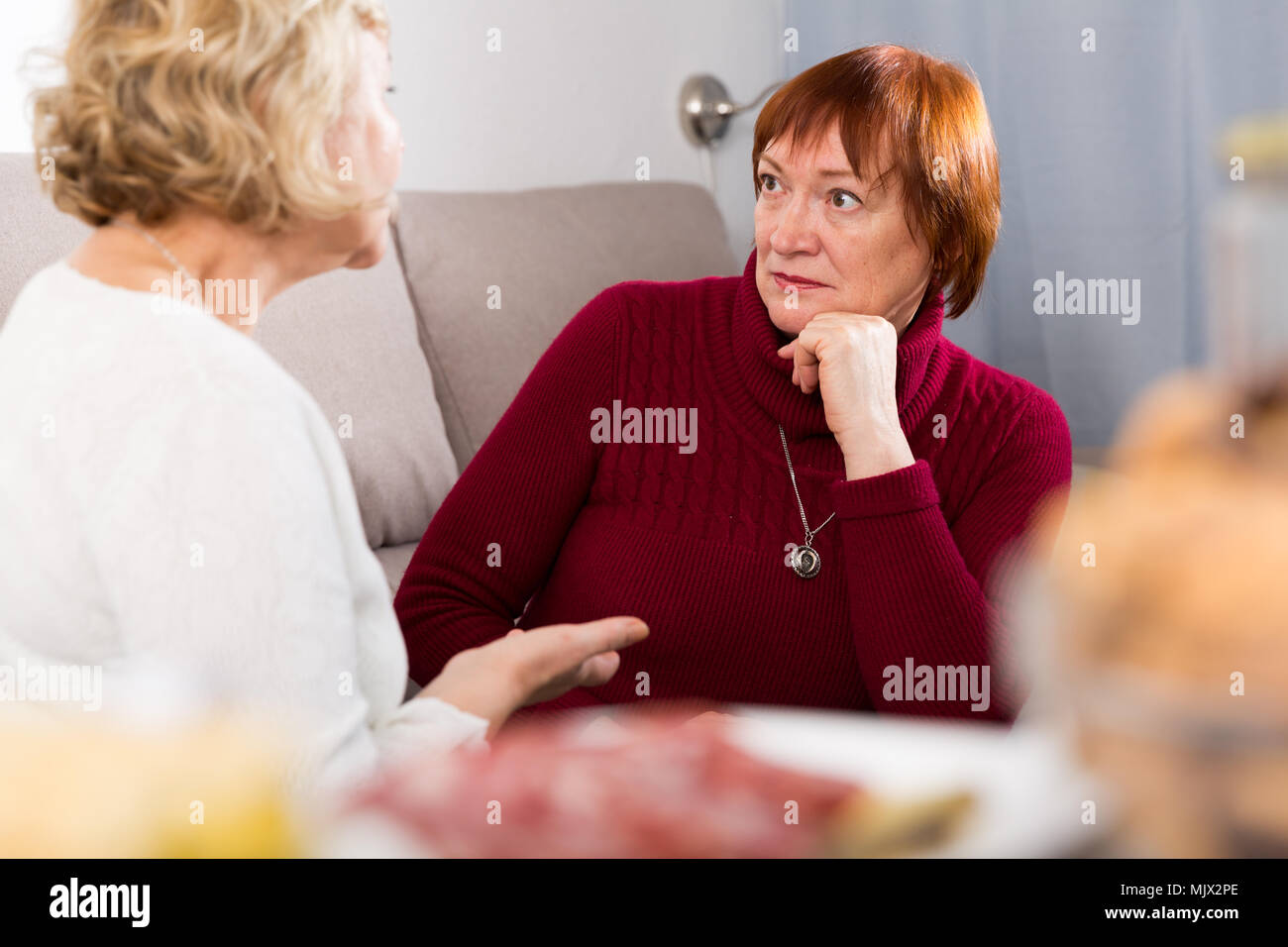 Unangenehm überrascht, ältere Frau sitzt auf einem Sofa ihre Freundin hören Stockfoto