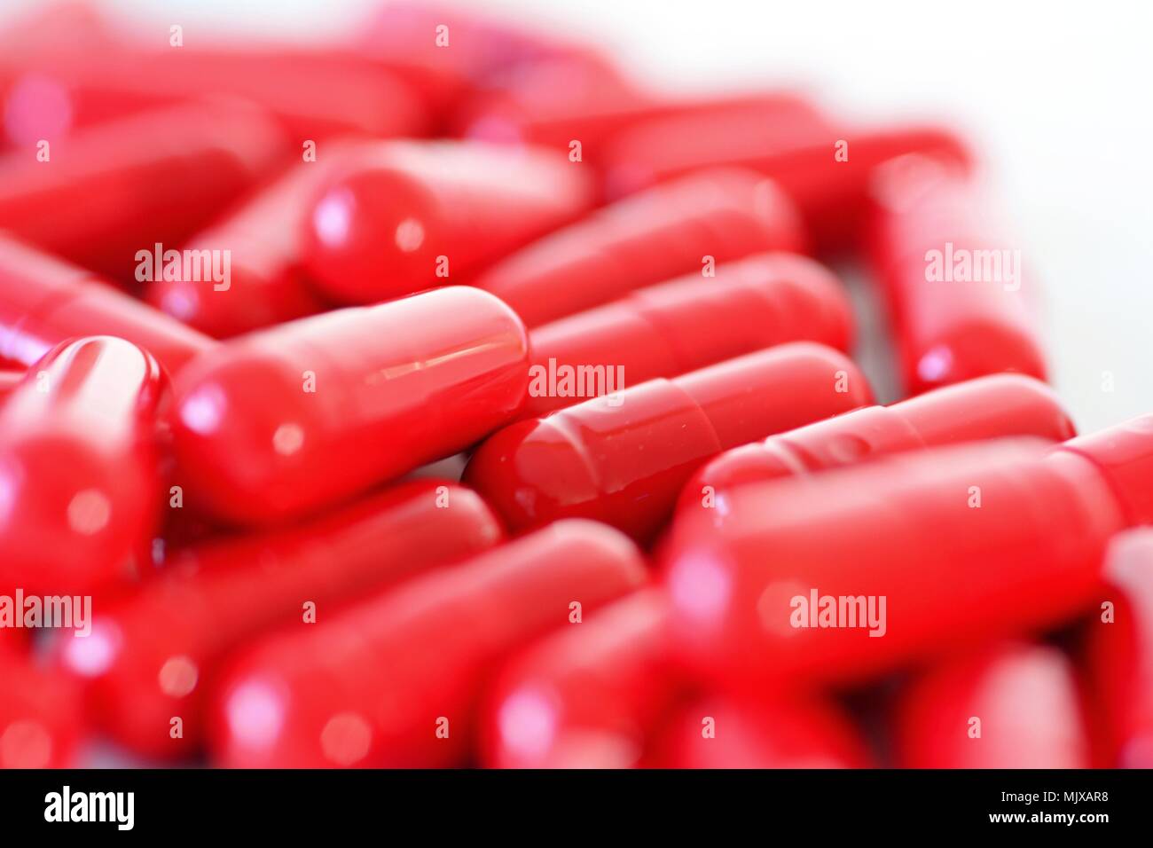 Heap eines roten Kapseln auf dem weißen Hintergrund verschüttet. Stockfoto