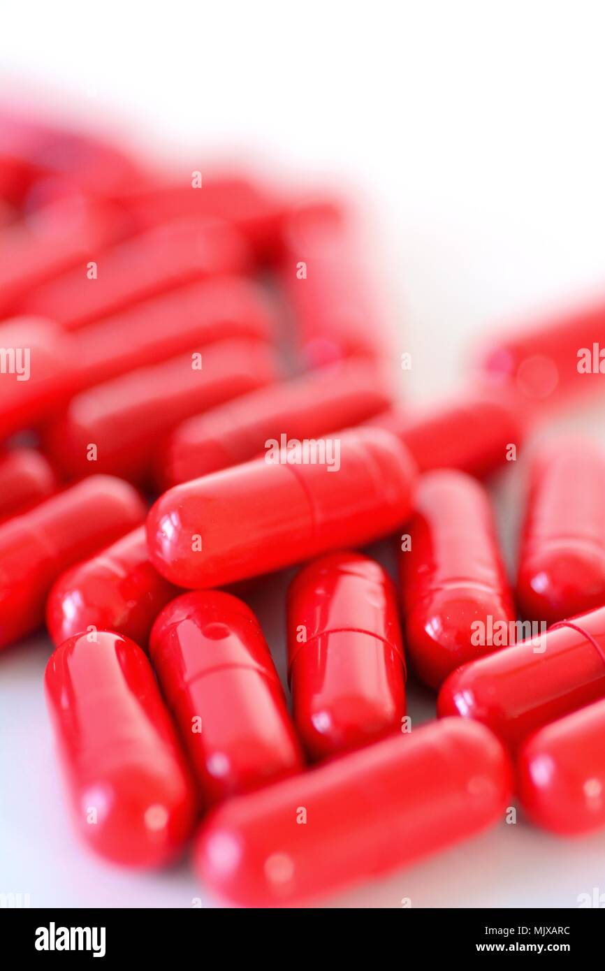 Heap eines roten Kapseln auf dem weißen Hintergrund verschüttet. Stockfoto