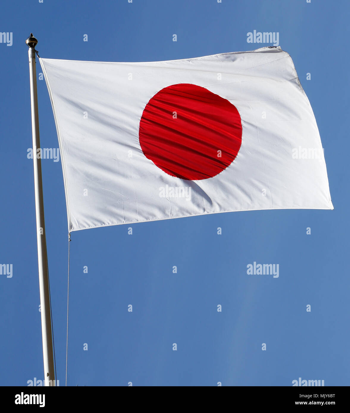 Die Flagge von Japan gegen den blauen Himmel gehoben. Stockfoto