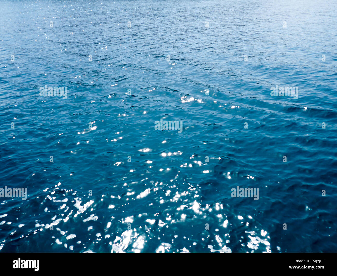 Wasser Oberfläche. Zusammenfassung Hintergrund, Meerwasser im Sonnenlicht. Sommer Hintergrund. Sonnenlicht bokeh funkelt tiefe türkisblaue wasser Mittelmeer verschwommen Stockfoto