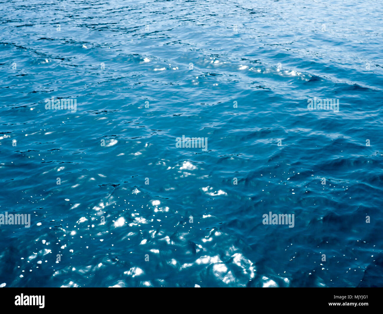 Wasser Oberfläche. Zusammenfassung Hintergrund, Meerwasser im Sonnenlicht. Sommer Hintergrund. Sonnenlicht bokeh funkelt tiefe türkisblaue wasser Mittelmeer verschwommen Stockfoto