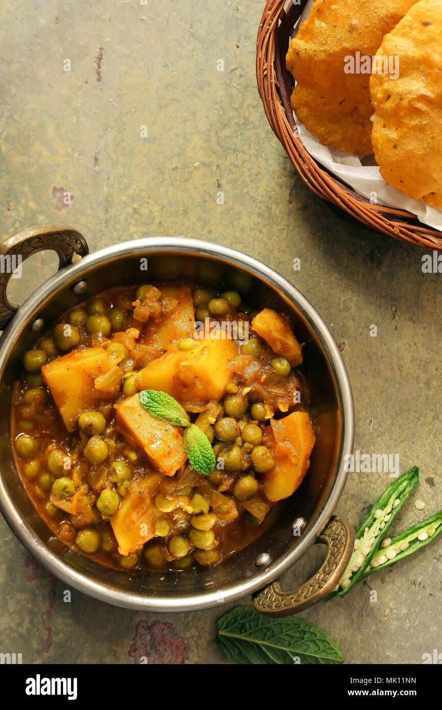 Hausgemachte Aloo Mutter - indische Curry mit Kartoffeln und Erbsen mit Poori/Puri, Ansicht von oben serviert. Stockfoto