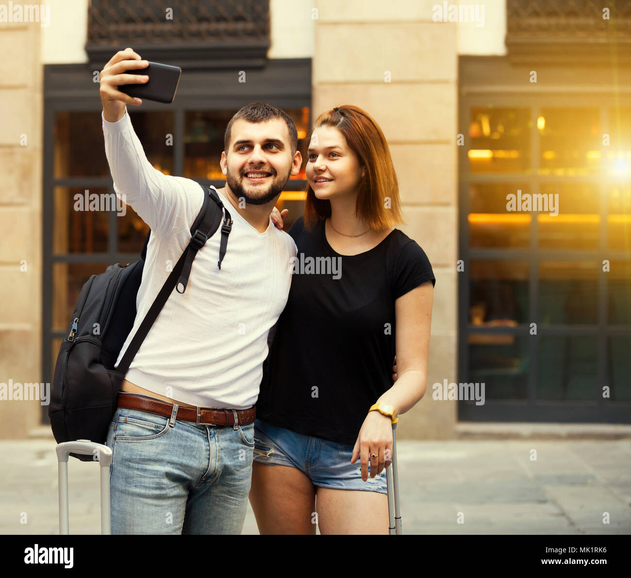 Lächelnd Spanisch weibliche und männliche stehend mit Gepäck auf der Straße und Unter selfie Stockfoto
