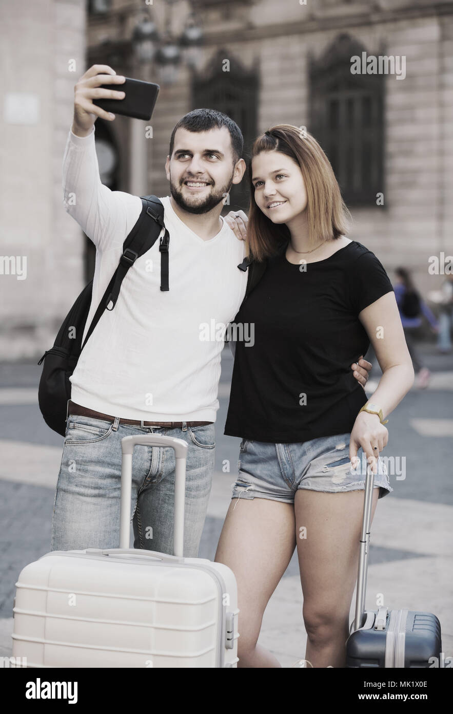 Lächelnde amerikanische weibliche und männliche stehend mit Gepäck auf der Straße und Unter selfie Stockfoto