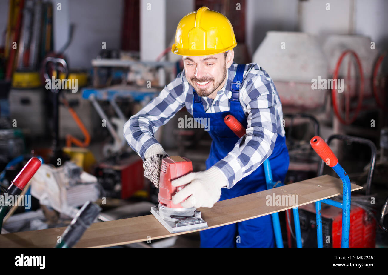 Mann 26-30 Jahre alt wird mit Schleifer für Bauarbeiten am Workshop. Stockfoto