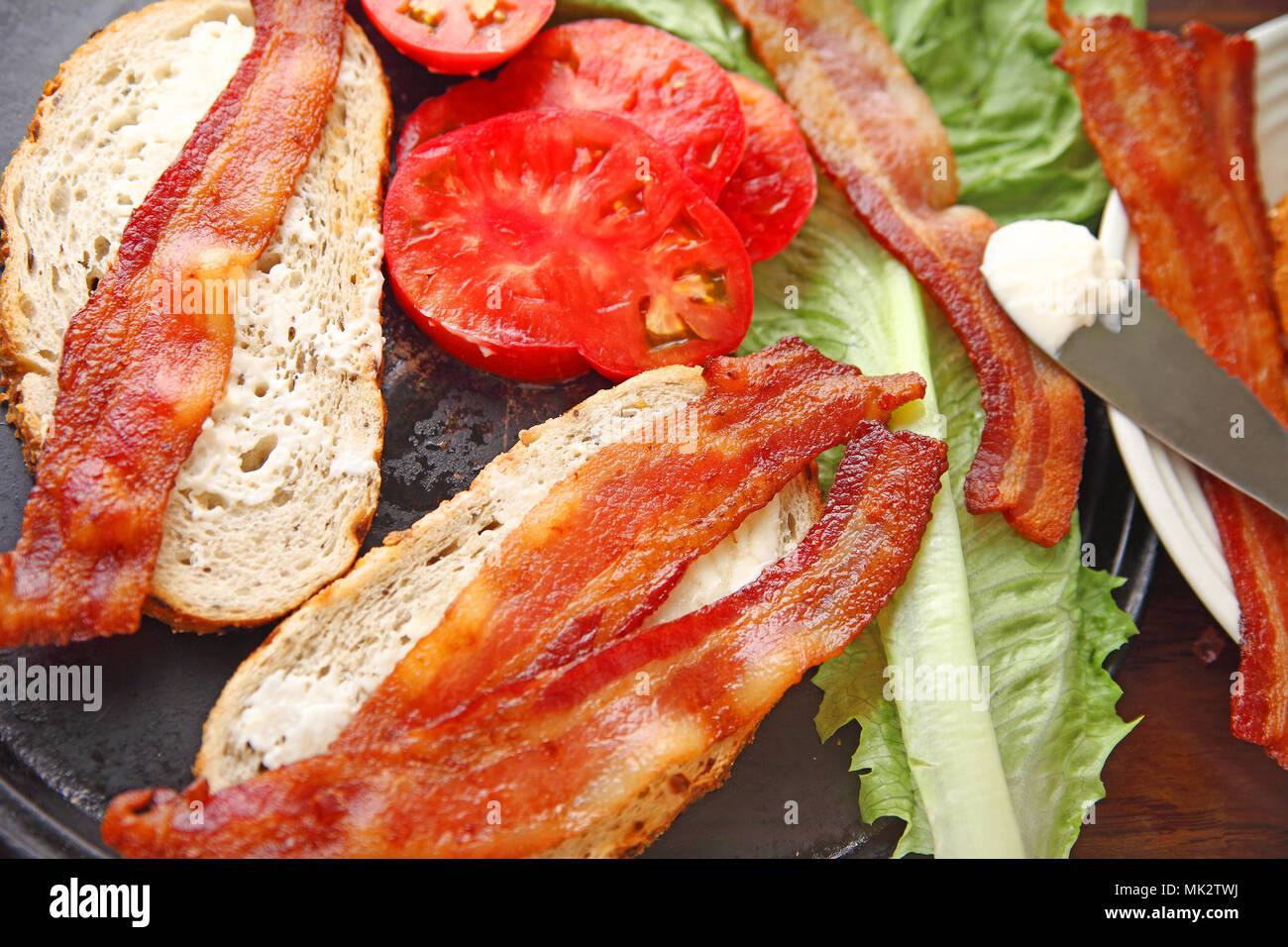 Alle Einzelteile, die benötigt werden, um eine Speck, Salat und Tomate Sandwich auf Zwiebel Roggenbrot zu machen Stockfoto