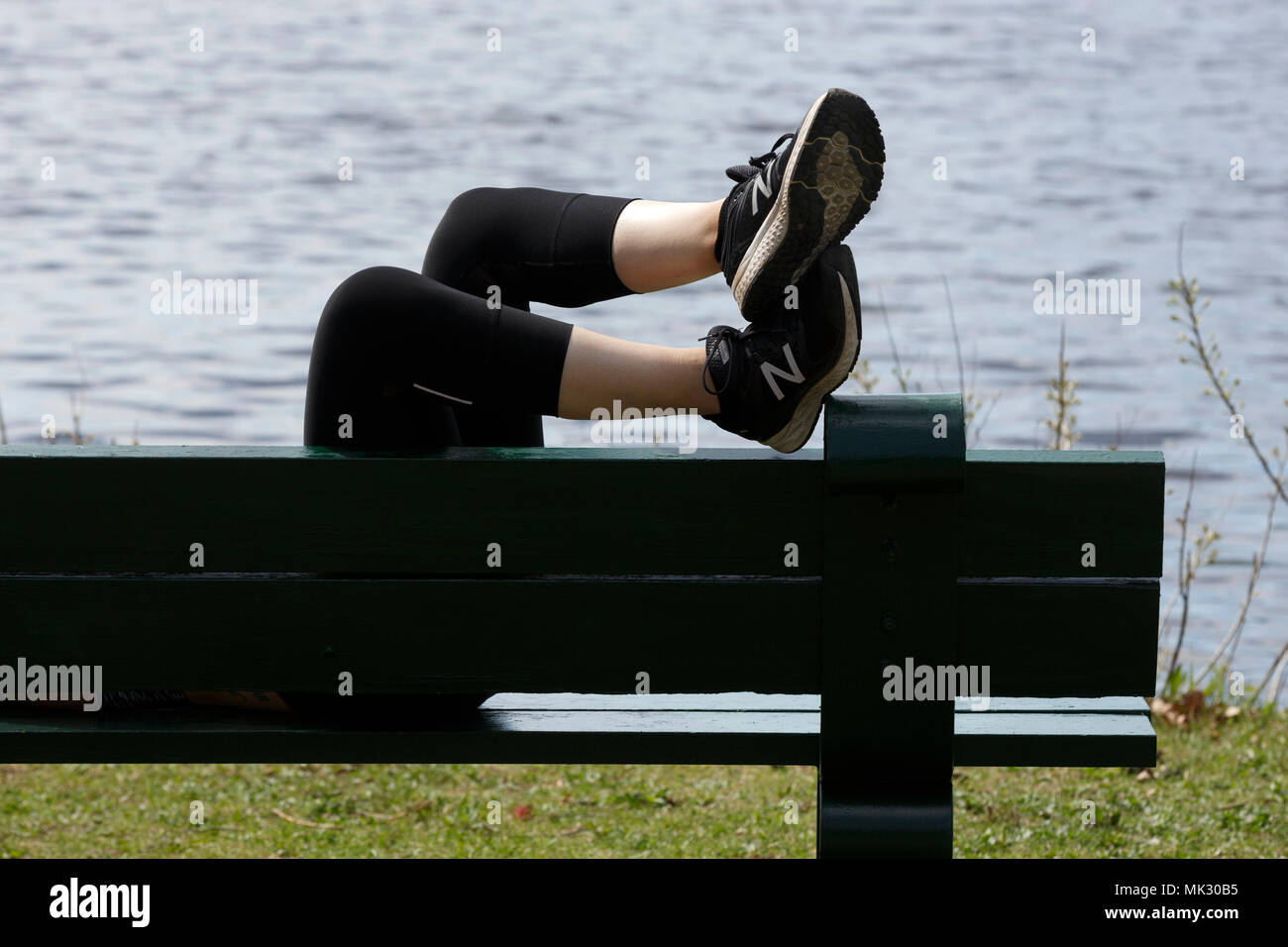 Person mit ihrer Füße hochlegen Relaxen auf einer Parkbank Charles River Esplanade, Boston, Massachusetts Stockfoto