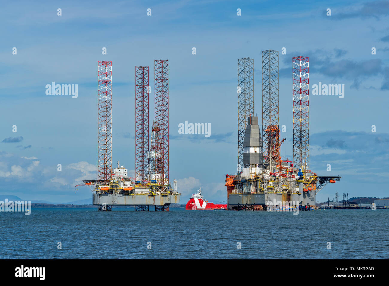 CROMARTY FIRTH SCHOTTLAND zwei AUSRANGIERTE ÖLBOHRINSELN bei Reparaturarbeiten liegen aus CROMARTY MIT ROTEN BOOT Stockfoto