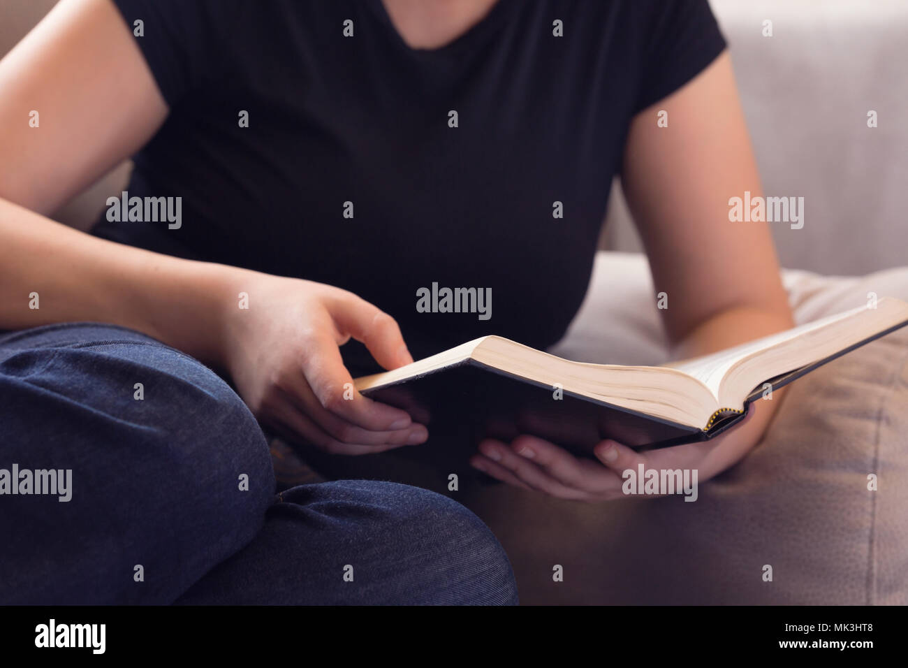 Junge Frau auf dem Sofa entspannen Lesen der Bibel Stockfoto