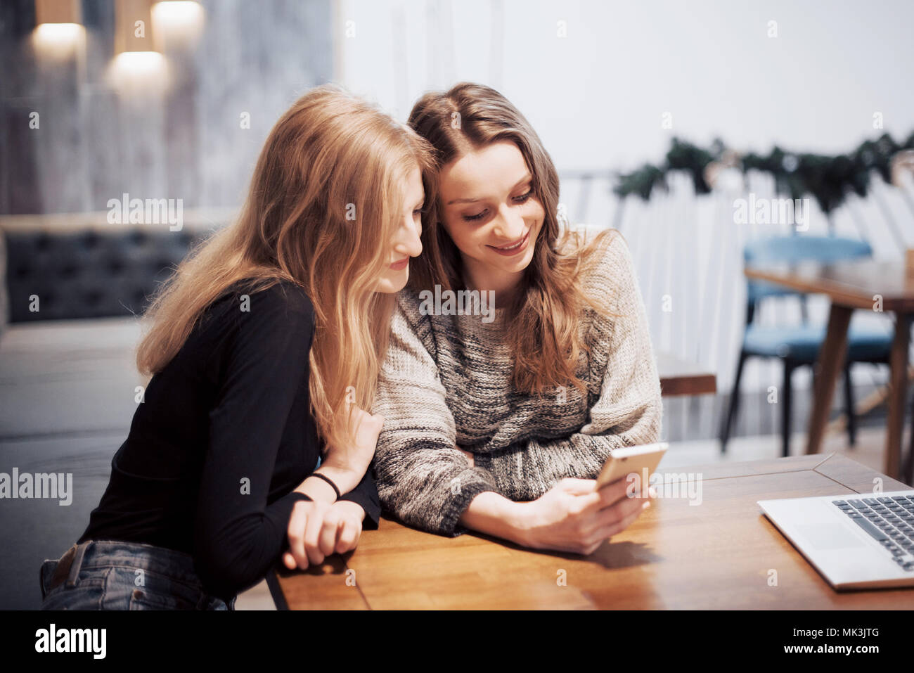 One-on-one Meeting. Zwei junge business Frauen am Tisch sitzen im Cafe. Mädchen zeigt ihrer Freundin Bild auf dem Bildschirm des Smartphones. Am Tisch ist Notebook geschlossen. Freunde treffen Stockfoto