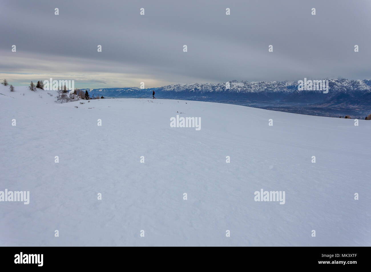 Man Walking auf Schnee, mit den Dolomiten im Hintergrund, Col Visentin, Belluno, Italien Stockfoto