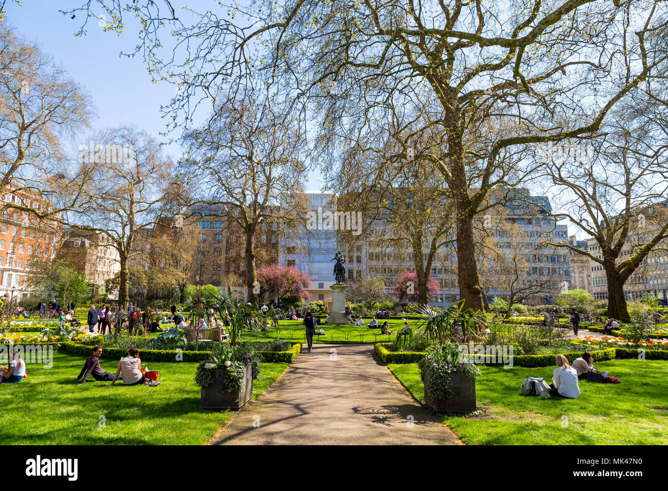 Leute sitzen auf das Gras und das Mittagessen in einem kleinen Stadtpark, St James's Square Garden, London, UK Stockfoto