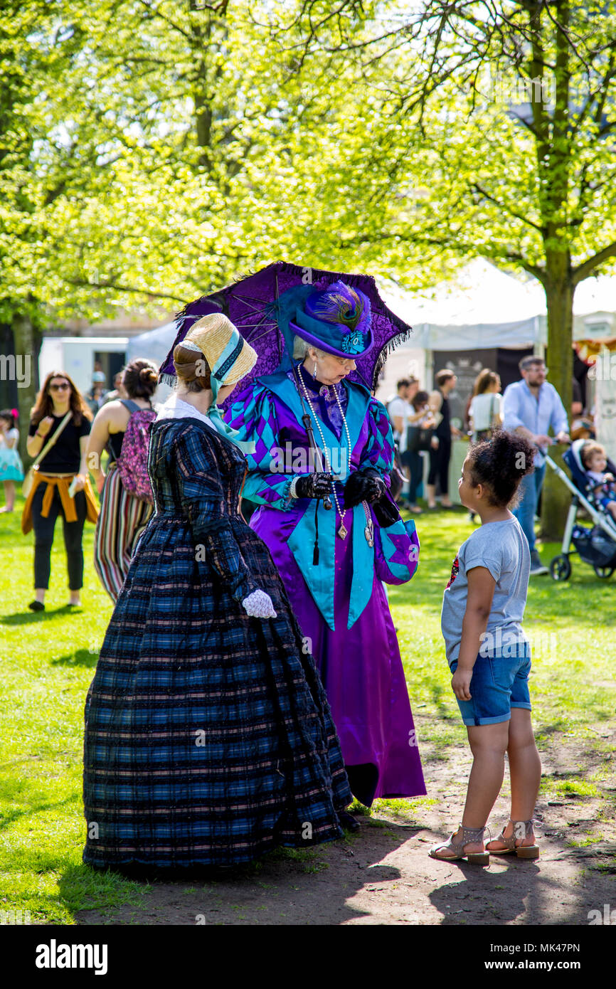 Zwei viktorianischen Damen in einem Garten, mit einem jungen Mädchen an der Fes-Tea-Val 2018 über nationale Kaffee Tag in Chiswick House & Gardens, London, UK stehend Stockfoto