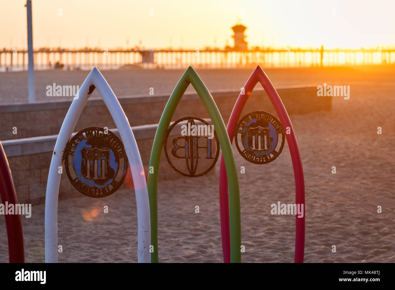 Sonnenlicht hinter dem ikonischen Huntington Beach Pier bei Sonnenuntergang in Huntington Beach, Kalifornien, USA Stockfoto