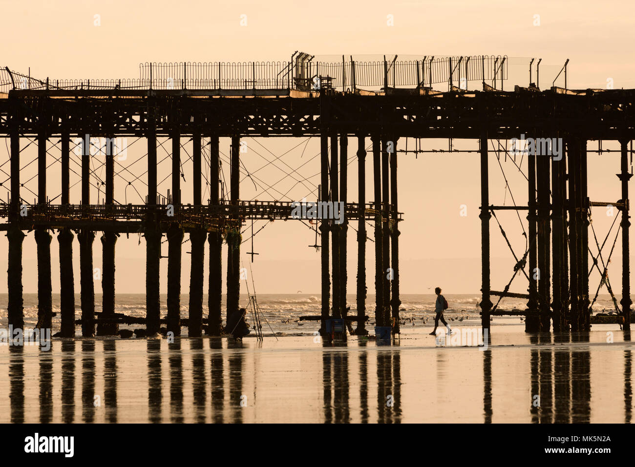 Silhouette einer Person, die unter dem Pier läuft Stockfoto