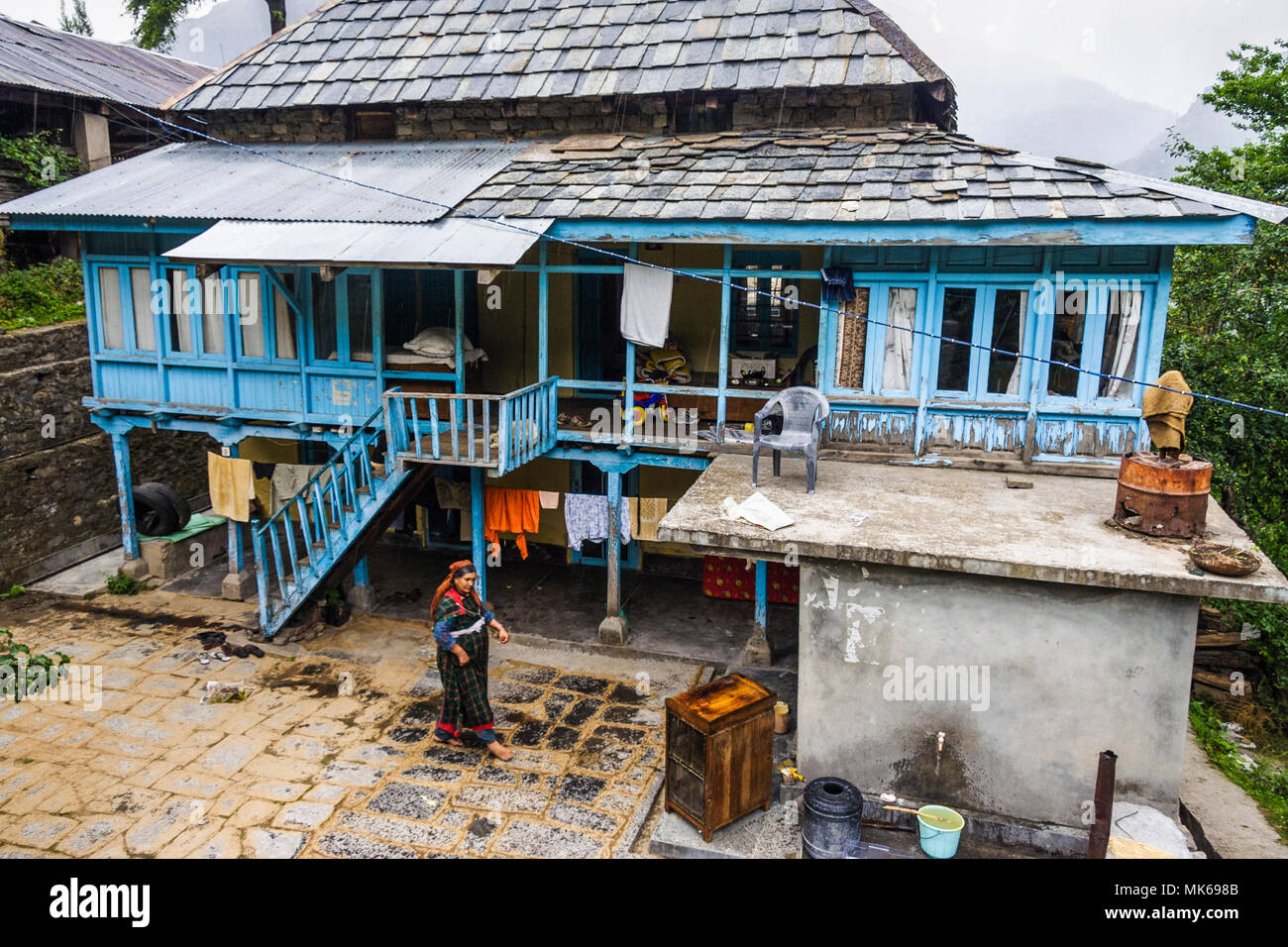 Nagar, Himachal Pradesh, Indien: Eine Frau geht über einen traditionellen Himachali Holzhaus in der historischen Stadt Naggar im Kullu Tal. Stockfoto