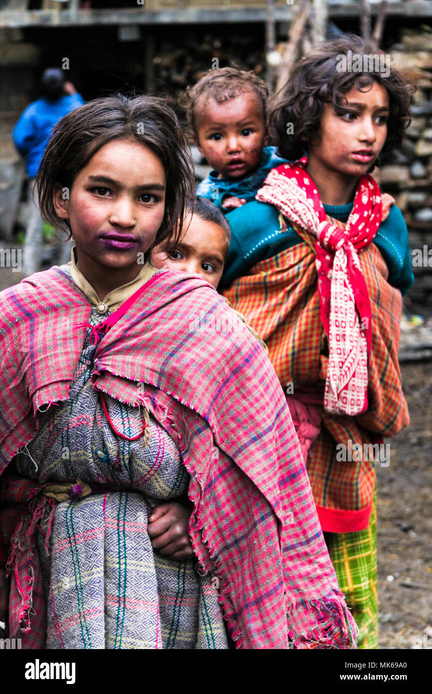 Malana, Himachal Pradesh, Indien: Portrait von Malanei Mädchen tragen Baby Kinder auf ihrem Rücken in dem abgelegenen Dorf Malana, isoliert auf einem kleinen Stockfoto