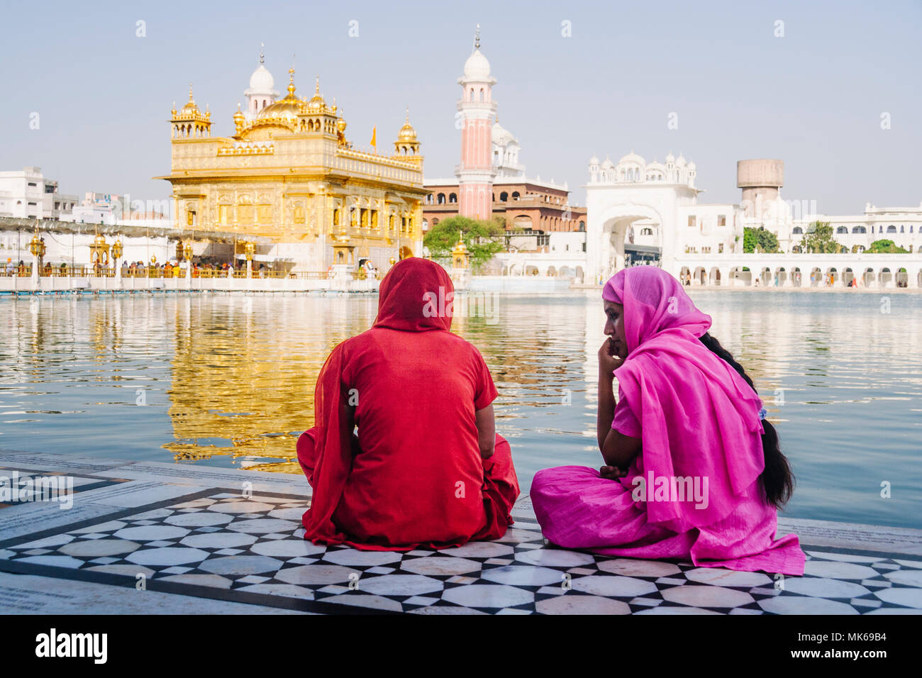 Amritsar, Punjab, Indien: Zwei Sikh pilgernden Frauen sitzen durch die Amrit Sarovar Pool im Goldenen Tempel. Stockfoto