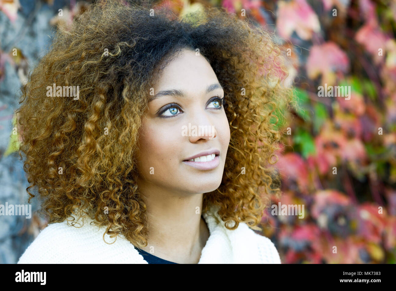Schone Junge Afrikanische Amerikanische Frau Mit Afro Frisur Und Grune Augen Tragen Weisse Winter Dress Mit Herbst Blatter Im Hintergrund Stockfotografie Alamy
