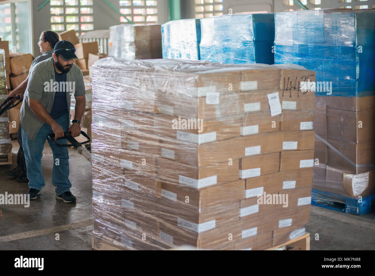 SAN JUAN, Puerto Rico - Seise, ein Recon Spezialist und Sprachwissenschaftler mit dem warfighter Disaster Response Team, bewegt sich Paletten mit Tausenden von Pfund von Lebensmitteln durch Neuseeland gespendet für die Distribution über Puerto Rico, Nov. 18, 2017. Sobald das Essen inszeniert wird, Mitglieder der Warfighters, arbeiten mit der Federal Emergency Management Agency, wird es für Familien noch zu verteilen, müssen nach der Zerstörung der Hurrikan Maria. Die Warfighters unterstützen die Erholung und Hilfsmaßnahmen auf Puerto Rico, und haben über 128.000 Mahlzeiten und 120 Paletten von Wasser, da Sie ankommen verteilt Stockfoto