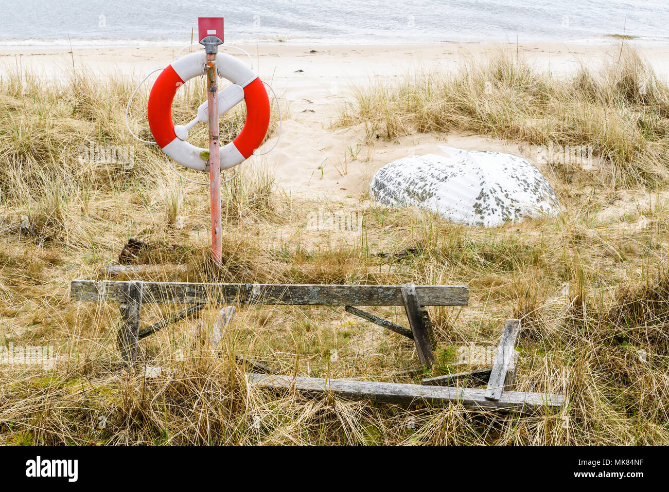 Ahus, Schweden. Rettungsring und Sand bedeckt Rettungsboot an einem Strand. Stockfoto