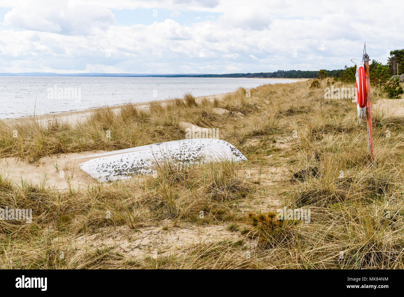 Ahus, Schweden. Rettungsring und Sand bedeckt Rettungsboot an einem Strand. Stockfoto