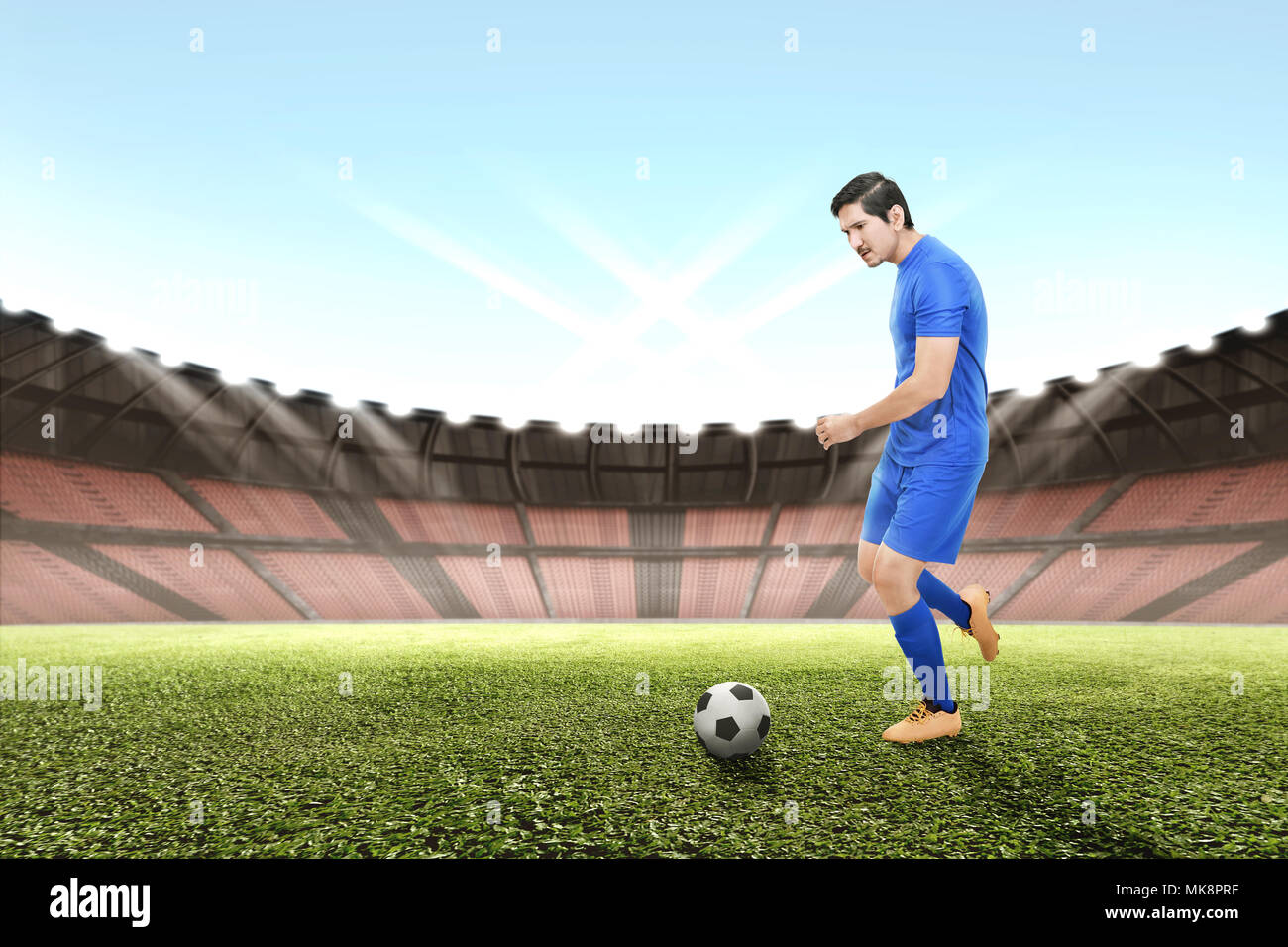 Seitenansicht des Asian Football Player Mann kicken den Ball auf dem Feld Stockfoto