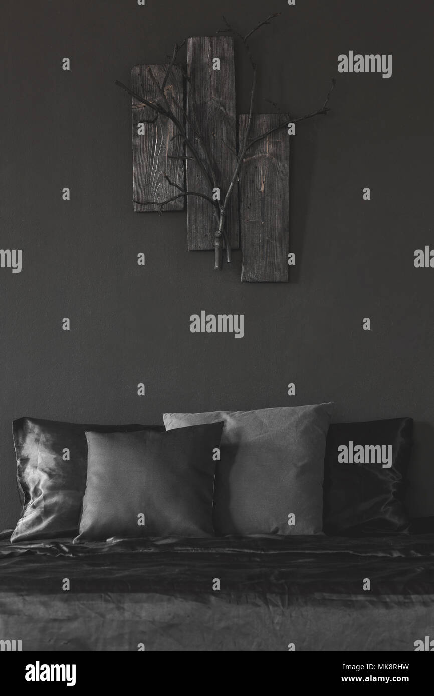 Holzdekor auf schwarze Wand über dem Bett mit Kissen in unicolor Schlafzimmer Innenraum Stockfoto