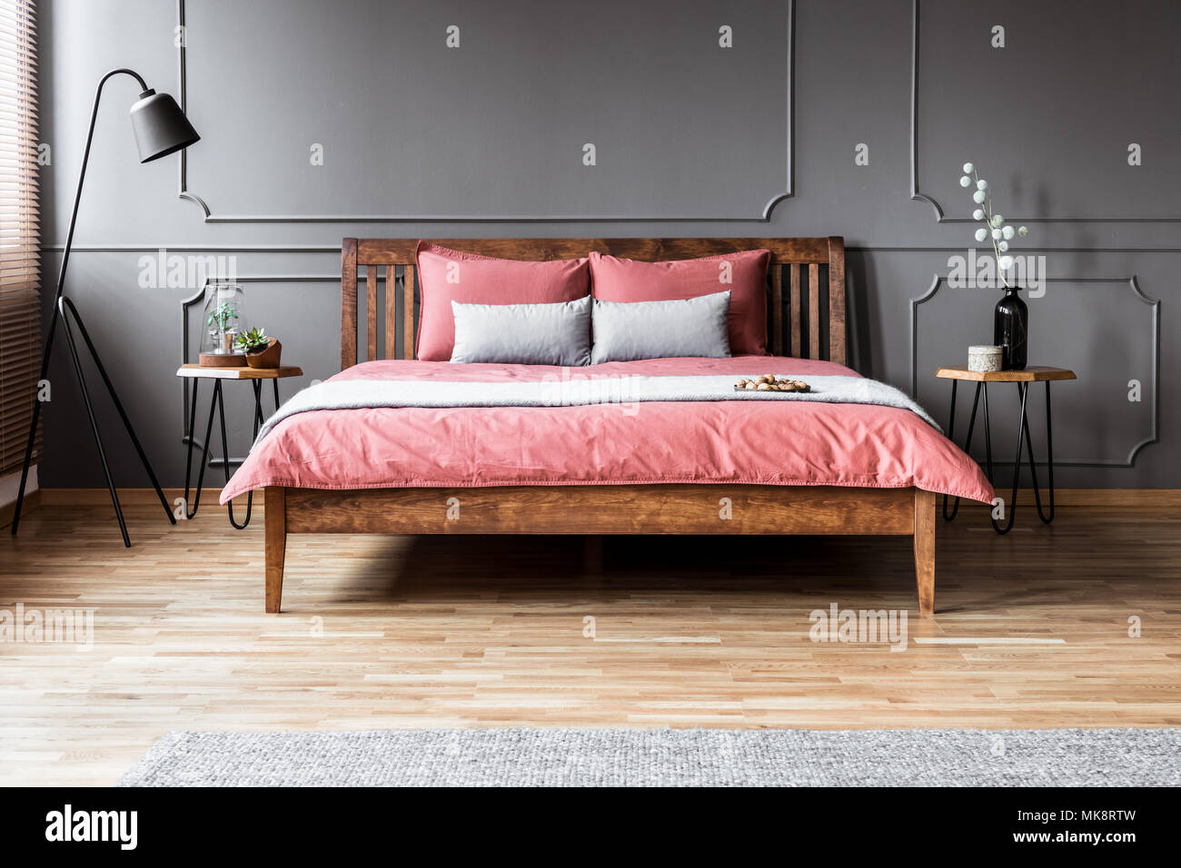 Grau und Rosa Kopfkissen auf dem Bett aus Holz im minimal Schlafzimmer  Innenraum mit schwarze Lampe und Leiste an der Wand Stockfotografie - Alamy