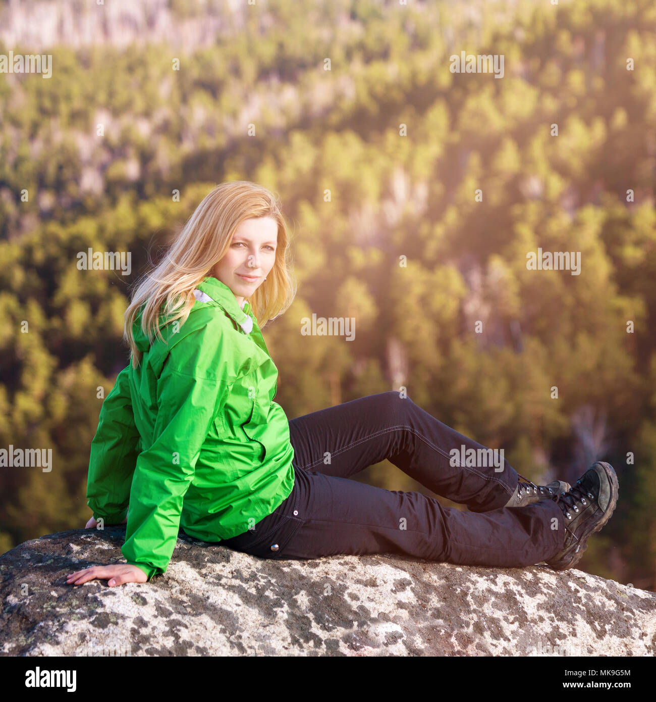 Junge Frau sitzt auf der Klippe. Stockfoto